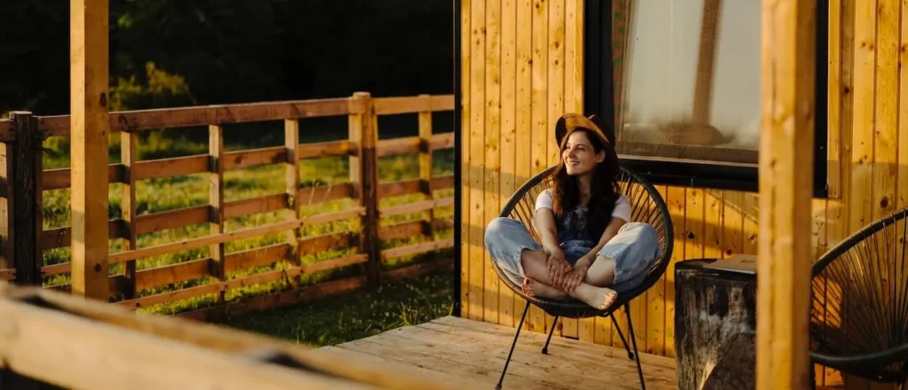 Young woman relaxing on the porch of a manufactured home.